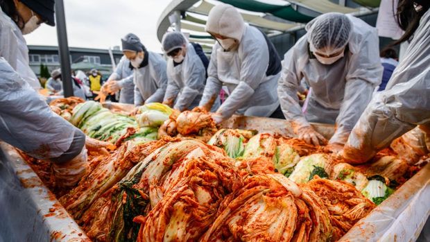 People take part in a kimchi making festival at Garak Market in Seoul on November 17, 2025. (Photo by ANTHONY WALLACE / AFP)