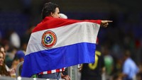 Beberapa di antara mereka membawa drum kecil dan memukulnya dalam ritme cepat, menciptakan irama yang memicu antusiasme di sekitar mereka. Yel-yel khas Paraguay juga menggema, menambah semangat menjelang pertandingan. Reuters/Daniel Jefferson