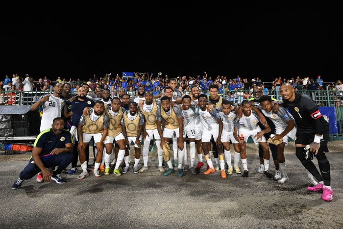 [UNVERIFIED CONTENT] View from the top of the cliffs at Lagun Beach towards the  beach, Curacao, Netherland Antilles.

A couple of persons can be seen walking towards the Caribbeans pristine and turquoise water. Also, it can be seen some colorful fisherman boats on the left side of picture.

The rocky cliffs and a partially cloudy sky can be seen at the background.