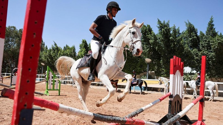 Seorang atlet memacu kudanya melompati rintangan dalam sesi latihan rutin. Meski kekurangan pendanaan, semangat untuk lolos kualifikasi Piala Dunia Tent-Pegging tetap menyala. Foto: REUTERS/Khaled Abdullah