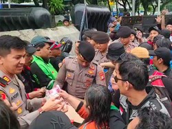 Anggota Polda Metro Bagikan Makan-Minum ke Massa Demo di Silang Monas