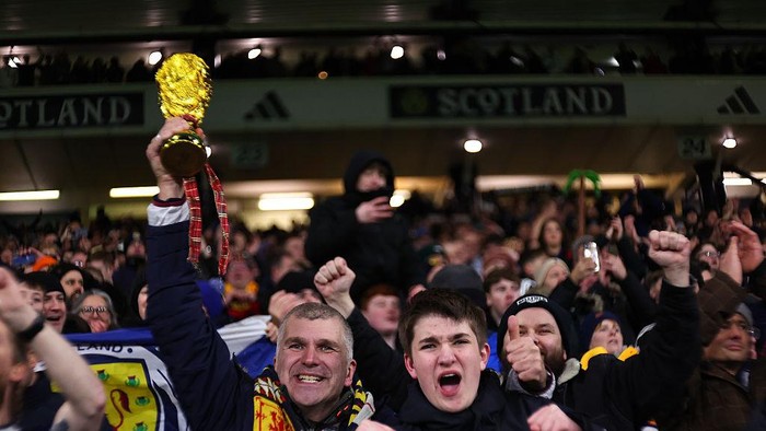 GLASGOW, SCOTLAND - NOVEMBER 18: A fan of Scotland celebrates with a replica World Cup Trophy during the FIFA World Cup 2026 qualifier match between Scotland and Denmark at Hampden Park on November 18, 2025 in Glasgow, Scotland. (Photo by Robbie Jay Barratt - AMA/Getty Images)