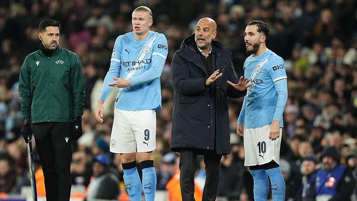 Manchester City substitutes Erling Haaland (centre left) and Rayan Cherki (right) wait to enter the pitch with manager Pep Guardiola during the UEFA Champions League, league phase match at the Etihad Stadium, Manchester. Picture date: Tuesday November 25, 2025. (Photo by Martin Rickett/PA Images via Getty Images)