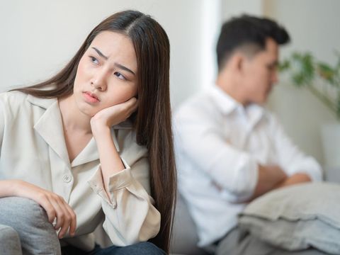 Young couple in quarrel at home.sadness young Asian woman sitting on sofa with boyfriends.relationship problems between couples and communication issues concept