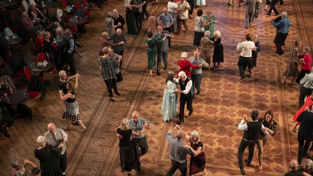 Ballroom dancers take part in a Tea Dance, accompanied by a live organist, in the Blackpool Tower Ballroom, in Blackpool, north west England on October 22, 2025. Tea dances, which evolved from the tradition of afternoon tea in the late 19th century, are enjoying a revival, especially since the pandemic. Often cited as an effective way to combat loneliness, the dances are also attributed to improving the participants' mental and physical health. Frequently hosted in Victorian and Edwardian-era halls, tea dances typically offer a mixture of ballroom and sequence dancing styles and feature refreshments of tea, coffee and cakes. (Photo by Oli SCARFF / AFP)