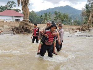 Jembatan Darurat Putus, Polisi Gendong Lansia Seberangi Sungai di Agam