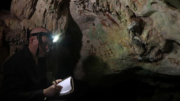 El investigador Maxime Aubert examina una antigua pintura rupestre en una cueva de piedra caliza llamada Liang Metanduno en Muna, una pequeña isla satélite frente a la península sureste de la isla indonesia de Sulawesi, en esta fotografía publicada el 21 de enero de 2026. Ahdi Agus Oktaviana/Handout vía REUTERS
