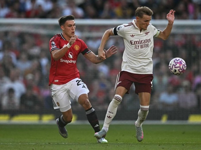 Manchester United's Uruguayan midfielder #25 Manuel Ugarte (L) vies with Arsenal's Norwegian midfielder #08 Martin Odegaard (R) during the English Premier League football match between Manchester United and Arsenal at Old Trafford in Manchester, north west England, on August 17, 2025. (Photo by Paul ELLIS / AFP) / RESTRICTED TO EDITORIAL USE. No use with unauthorized audio, video, data, fixture lists, club/league logos or 'live' services. Online in-match use limited to 120 images. An additional 40 images may be used in extra time. No video emulation. Social media in-match use limited to 120 images. An additional 40 images may be used in extra time. No use in betting publications, games or single club/league/player publications. /
