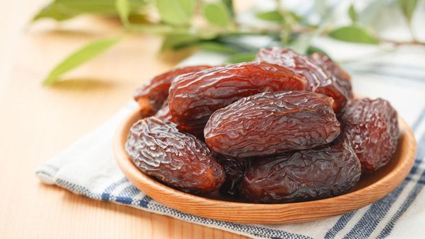 Date fruit in wood bowl on placemat, Dried date palm fruits top view