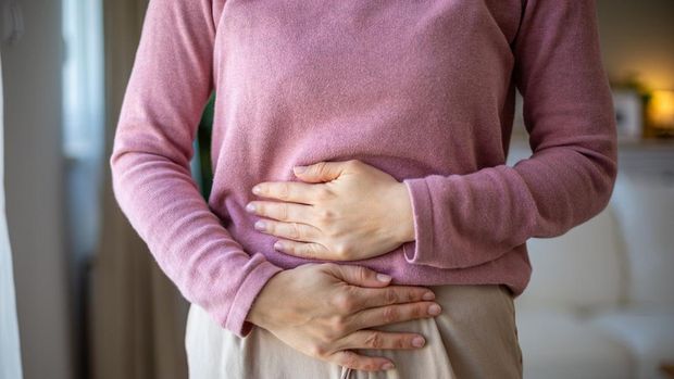 Mid adult woman holding her belly suffering from abdominal pain