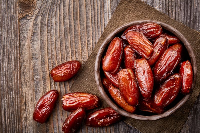 Kurma Bowl of dried dates on wooden background from top view
