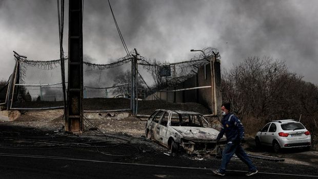 A man walks past a destroyed car as smoke rises after a reported strike on Shahran fuel tanks, amid the U.S.-Israeli conflict with Iran, in Tehran, Iran, March 8, 2026. Majid Asgaripour/WANA (West Asia News Agency) via REUTERS ATTENTION EDITORS - THIS PICTURE WAS PROVIDED BY A THIRD PARTY     TPX IMAGES OF THE DAY