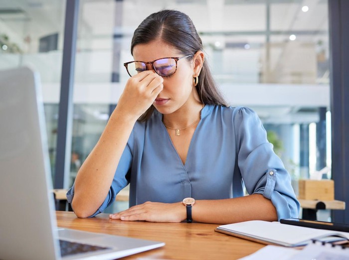 Stress headache, burnout and woman in office overwhelmed with workload at desk with laptop. Frustrated, overworked and tired woman with computer at startup, anxiety from deadline time pressure crisis