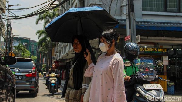 Jakarta Memanas, Warga Berlindung dari Terik dengan Payung