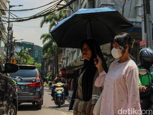 Jakarta Memanas, Warga Berlindung dari Terik dengan Payung