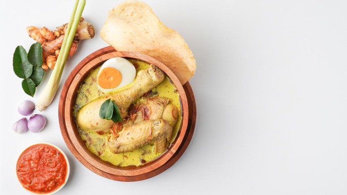 Lontong opor ayam is an Indonesian traditional dish usually served during eid Mubarak, Eid al Fitr holiday celebration with Ketupat Lebaran or rice cake dumpling and sambal chili sauce.