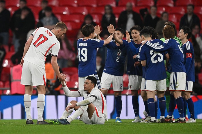 LONDON, ENGLAND - MARCH 31: Dan Burn and Morgan Rogers of England look dejected as Japan players celebrate victory after the international friendly match between England and Japan at Wembley Stadium on March 31, 2026 in London, England. (Photo by Mik