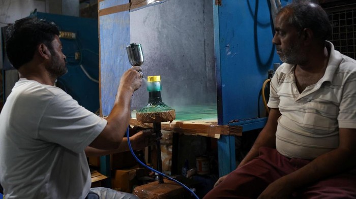 Konflik Timur Tengah Lumpuhkan Industri Kaca India A worker checks the quality of bottles being manufactured inside a glass factory amid fuel supply disruptions following the U.S.-Israeli conflict with Iran, in Firozabad in the northern state of Uttar Pradesh, India, March 26, 2026. REUTERS/Bhawika Chhabra