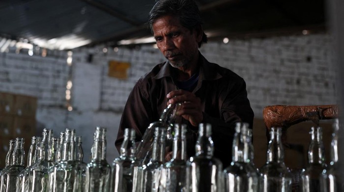 Konflik Timur Tengah Lumpuhkan Industri Kaca India A worker checks the quality of bottles being manufactured inside a glass factory amid fuel supply disruptions following the U.S.-Israeli conflict with Iran, in Firozabad in the northern state of Uttar Pradesh, India, March 26, 2026. REUTERS/Bhawika Chhabra