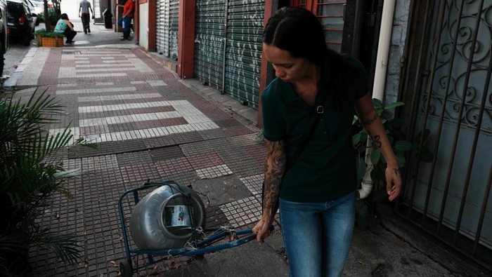 Harga Gas Melonjak, Program “Gas Rakyat Maria Luiza Pereira, 27, speaks to a friend (not pictured) as she leaves at home a cooking gas cylinder from the Brazil President Luiz Inacio Lula da Silva's flagship energy initiative, the “People's Gas” program, as the U.S.-Israeli war on Iran has sharply boosted liquefied petroleum gas prices in the country, Sao Paulo, Brazil, April 6, 2026. REUTERS/Alexandre Meneghini