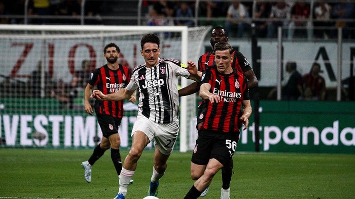 Juventus midfielder Andrea Cambiaso (27) competes for the ball against Milan midfielder Alexis Saelemaekers (56) during the Serie A football match number 34 between Milan and Juventus at the Stadio Giuseppe Meazza in Milan, Lombardy, Italy, on April 