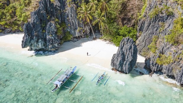 Pantai Entalula di Filipina View from above, stunning aerial view of a person on the Entalula Beach, a white sand beach bathed by a crystal clear water. Entalula island, Bacuit Bay, El Nido, Palawan, Philippines.