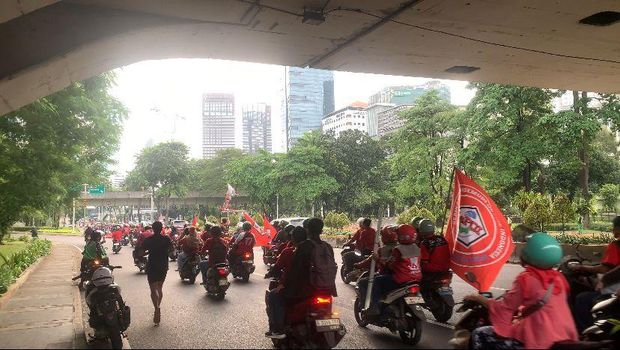 Sejumlah massa pekerja melakukan konvoi mengikuti seremoni Hari Buruh Internasional alias May Day 2026 ke Monas, Jakarta Pusat. Mereka mengenakan baju senada dan membawa bendera asosiasi.