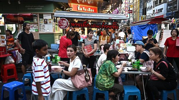 This photo taken on April 29, 2026 shows people eating noodles from a street food stall in Chinatown in Bangkok. Across Bangkok, aromas of garlic, chilli and grilled meat drift from roadside stalls and carts, but tighter controls on vendors threaten livelihoods and the street food culture that defines the Thai capital. (Photo by Lillian SUWANRUMPHA / AFP) / To go with AFP story Thailand-Bangkok-food-culture-economy,FOCUS by Montira Rungjirajittranon