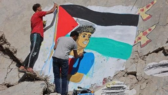 Palestinian artists paint a mural depicting football player Lamine Yamal waving a Palestinian flag during the Catalans title parade, on the rubble of buildings destroyed during the war, at Shati (Beach) refugee camp in Gaza City on May 13, 2026. The