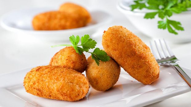 Makanan Spanyol Croquettes Homemade gourmet croquettes on a white plate with fork.