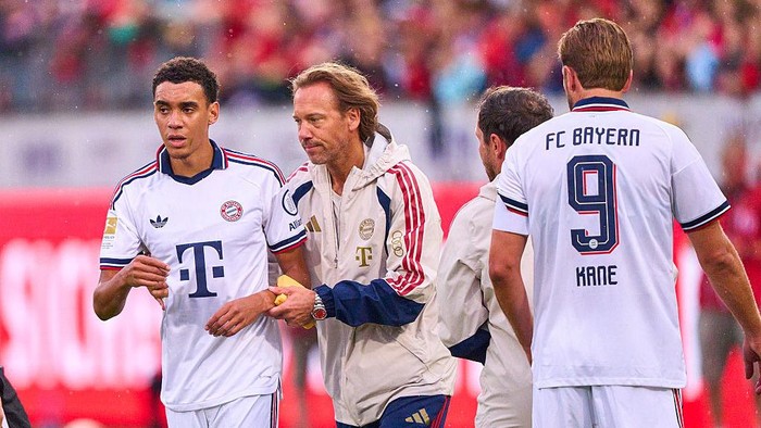 HEIDENHEIM, GERMANY - AUGUST 18: Jamal Musiala of FC Bayern Mnchen falls over during the match and requires treatment by FCB team doctor Prof. Dr. Peter Ueblacker during the preseason friendly match between 1. FC Heidenheim and FC Bayern Mnchen at Vo