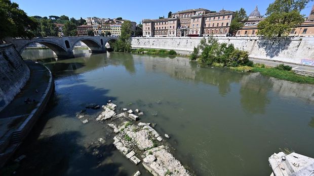 jembatan nero yang muncul lagi di Roma This photograph shows an Ancient Roman bridge emerging from the Tiber River, near the St. Peter Doome's Basilica at the Vatican City (R), in central Rome on 13 August, 2026. The unusually low waters of the Tiber River have revealed the remains of an ancient Roman bridge believed to date back to the reign of Emperor Nero (54-68 AD). Located near Castel Sant'Angelo, the structure once carried the ancient Via Triumphalis across the river, linking Rome with the Vatican area nearly 2000 years ago. (Photo by Andreas SOLARO / AFP)
