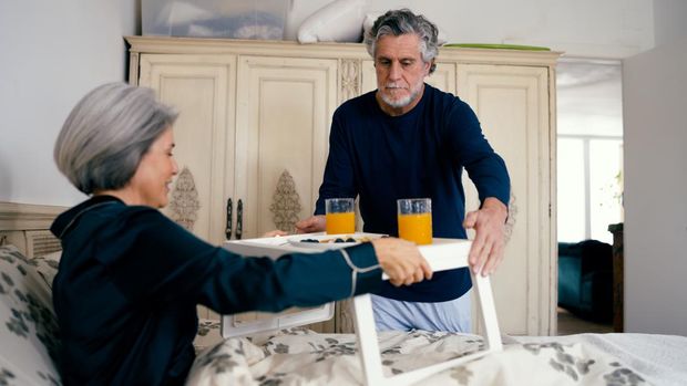 lansia sedang menggunakan overbed table Menggunakan overbed table atau meja lipat bisa mempermudah aktivitas lansia di atas tempat tidur.