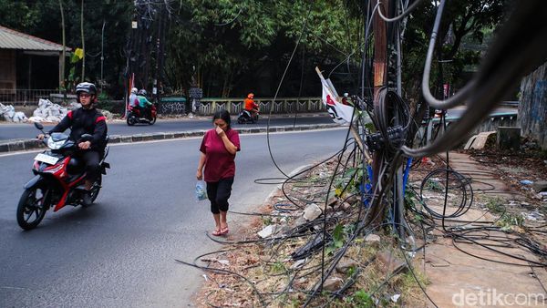 Semrawut! Kabel Fiber Optik Bergelantungan di Jalan Raya Cirendeu