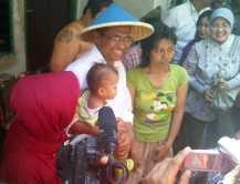 Tarik Pengunjung Pasar, Dahlan Bercaping Sambil Gendong Anak