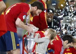 Xabi Alonso dibantu putri kecilnya mengangkat tropi. REUTERS/Alessandro Bianchi.