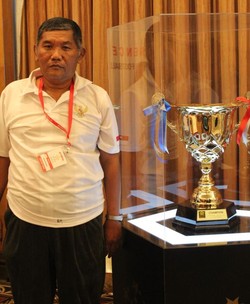 Asisten pelatih tim Yamaha U-13 Indonesia, Bambang Murdijatno, berpose di samping trofi turnamen. Indonesia, juara 2010 dan runner-up 2011, bertekad memboyong kembali piala ini ke tanah air.