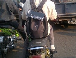 Pengendara Motor dengan Nomor Polisi di Tas Punggung