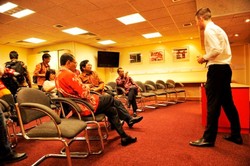 Seorang tour guide sedang menjelaskan fungsi ruangan pers di dalam stadion Anfield. Ruangan ini terlihat sumpek dan terasa kecil untuk tim sekelas Liverpool.