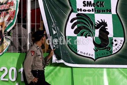 Seorang polisi mengintip suporter Medan dari balik poster SMeCK Hooligan ( Suporter Medan Cinta Kinantan) yang dipasang di pagar tribun penonton Stadion Kaharudin Nasution Rumbai, Pekanbaru.