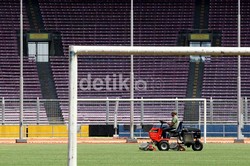 Sebagian petugas merapikan rumput stadion.