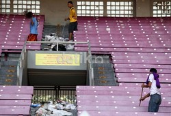 Tiga orang petugas membersihkan sampah di areal tribun penonton.