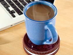 Kopi Tetap Hangat dengan Laptop dan Sekeping Biskuit