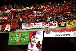 Suporter Indonesia yang memakai atribut merah putih meneriakkan yel-yel dukungan dari atas tribun.
