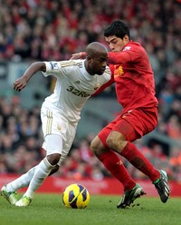     Luis Suarez berusaha menghadang Dwight Tiendalli. Dalam pertandingan ini, Suarez membobol gawang Swansea di menit ke-56. AFP/Lindsey Parnaby.