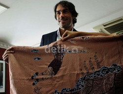 Robert Pires memperlihatkan batik bergambar pemain volly yang diterimanya dari Menpora.