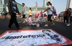 Sejumlah warga yang tengah melakukan aktifitas olahraga, melintas di depan spanduk Bepe For Persija, yang telah ditanda tangani oleh para suporter The Jak Mania.