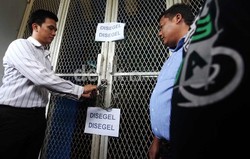 Seorang petugas dari identifikasi dari Polda Metro Jaya membuka pintu kantor PSSI yang disegel.