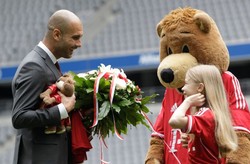 Diberi bunga oleh seorang anak perempuan dan maskot klub, Bernie. Guardiola dikontrak tiga tahun oleh Bayern Munich, untuk melanjutkan pekerjaan Jupp Heynckes yang musim lalu mempersembahkan tiga gelar: Bundesliga, Piala Liga, dan Liga Champions. (REUTERS/Michaela Rehle)