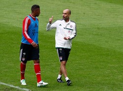 Guardiola berbincang-bincang dengan pemain bertahan Bayern, Jerome Boateng. Ia mengatakan, sejak didekati Bayern setahun lalu, ia langsung belajar bahasa Jerman untuk mempermudah komunikasinya dengan para pemain. (REUTERS/Michaela Rehle)